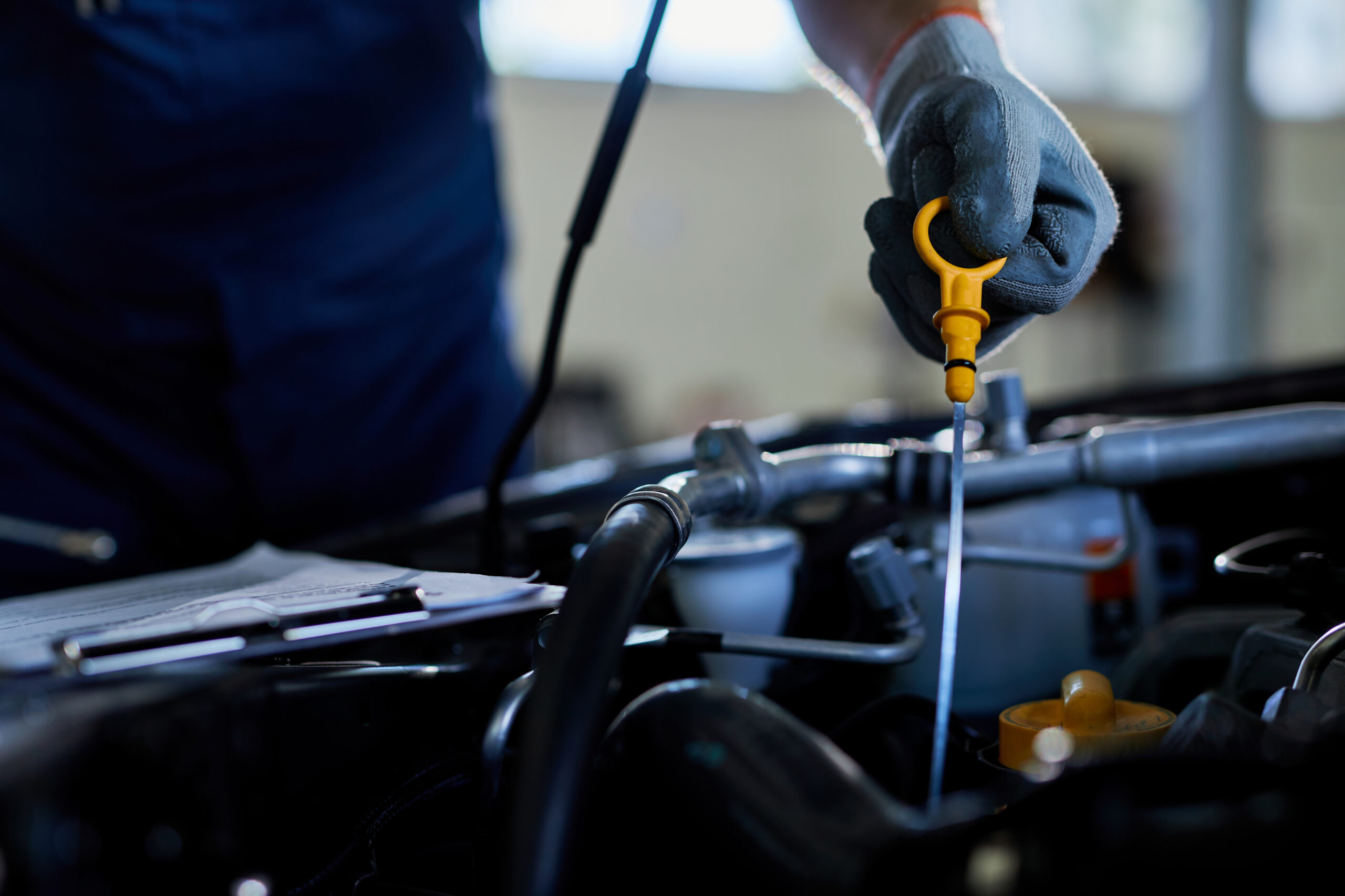 A person checking engine oil with a dipstick in a car engine.