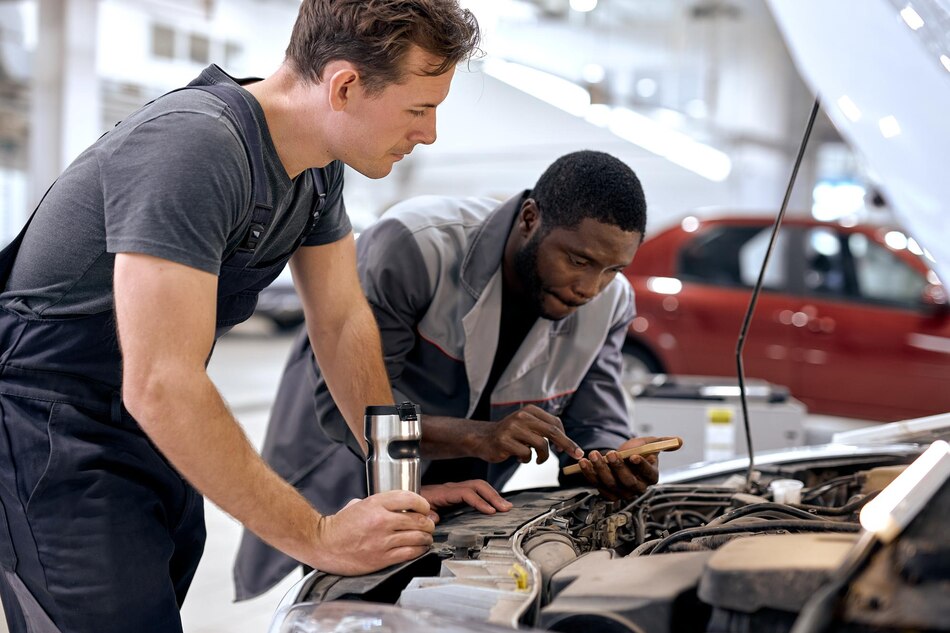 Two mechanics inspecting a car engine in a garage.