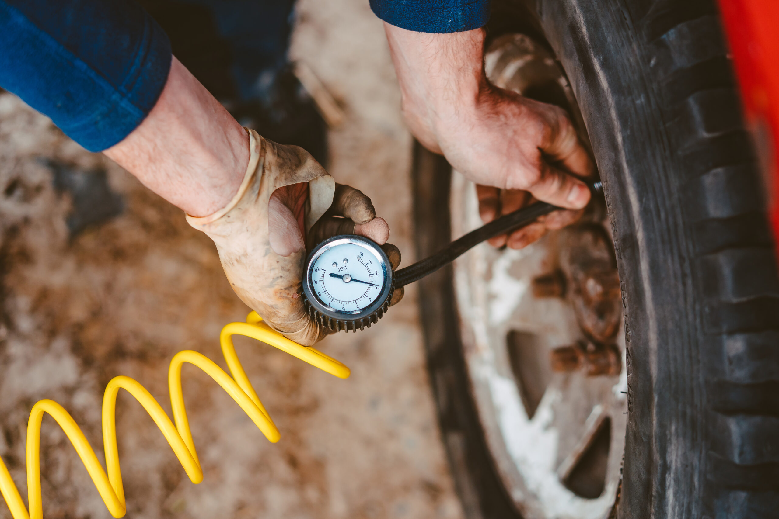 A person checking tire pressure with a gauge on a car wheel.