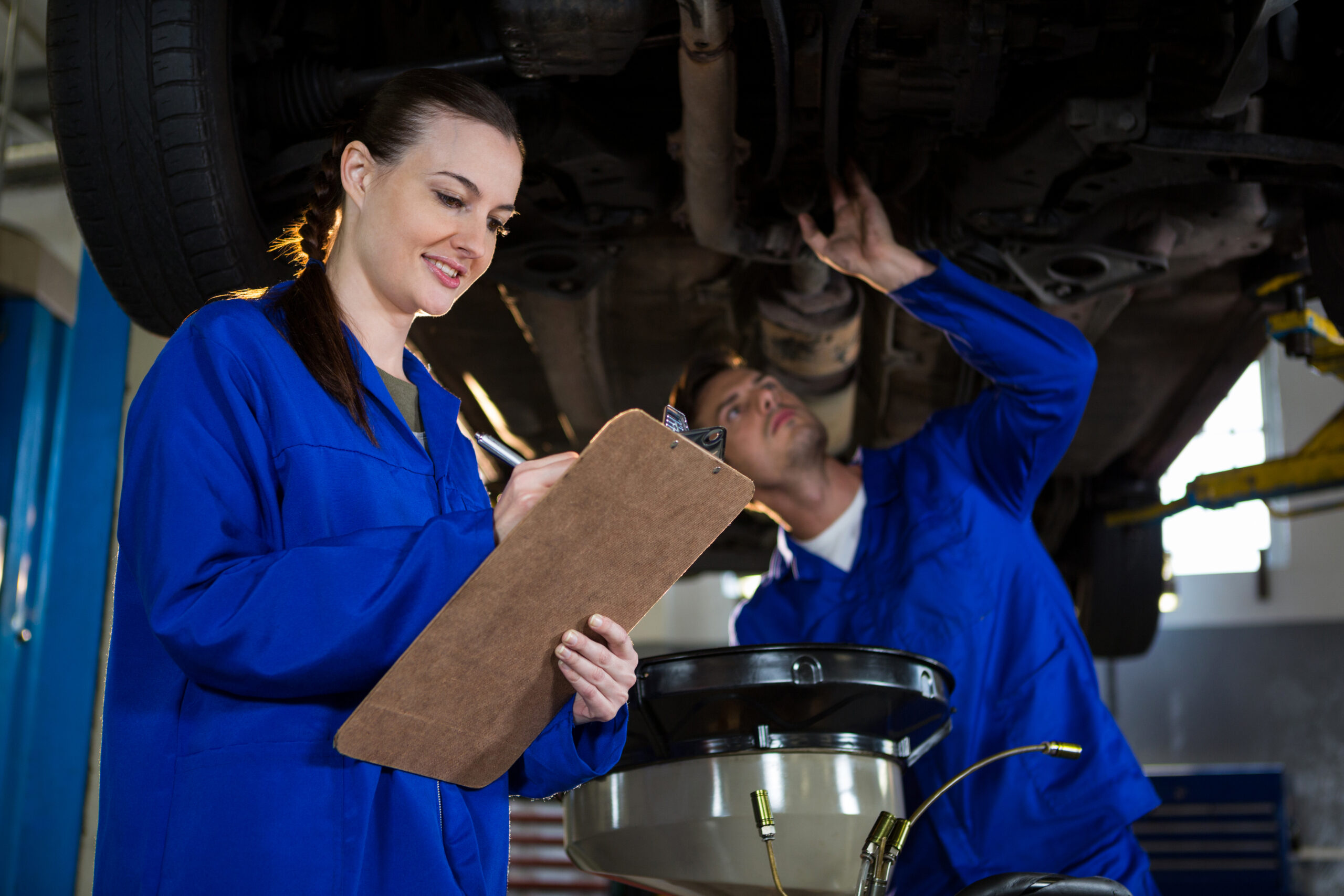 Two women in blue uniforms working with machinery.